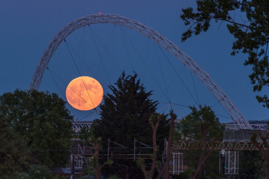Strawberry Moon, rises behind Wembley Stadium in north west London