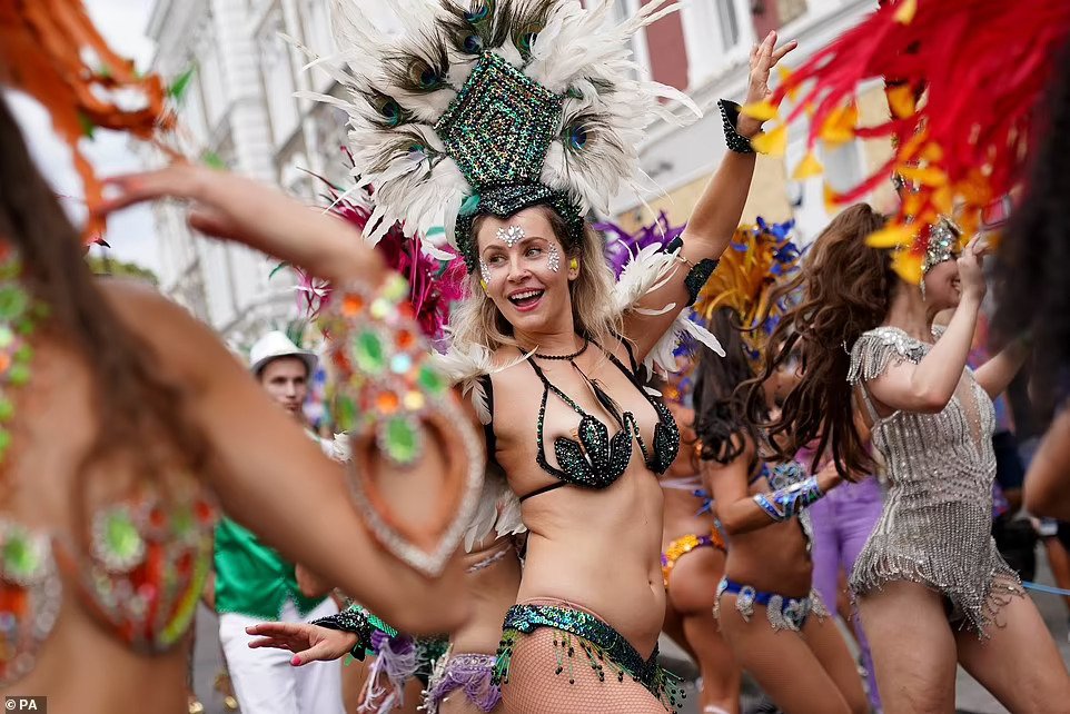 Performers in striking outfits dance along the streets as huge crowds watch on during day two of Notting Hill Carnival 2022